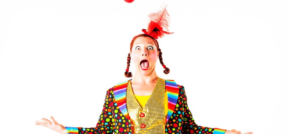 A clown juggling four red balls