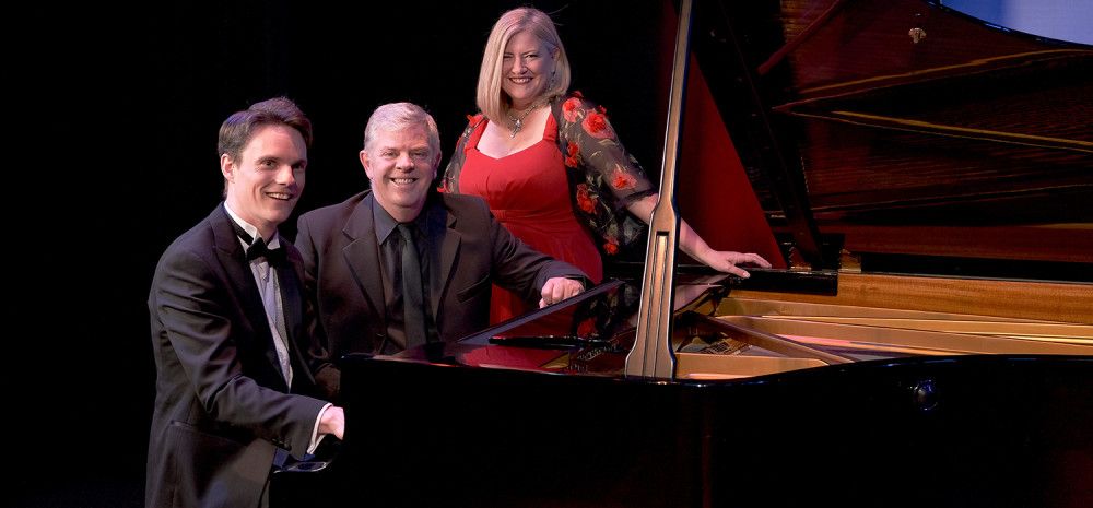 Three people sitting at a piano
