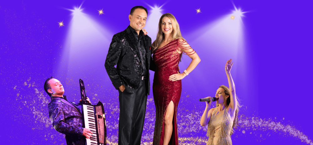 A couple stand against a purple background with a spot lights shining down