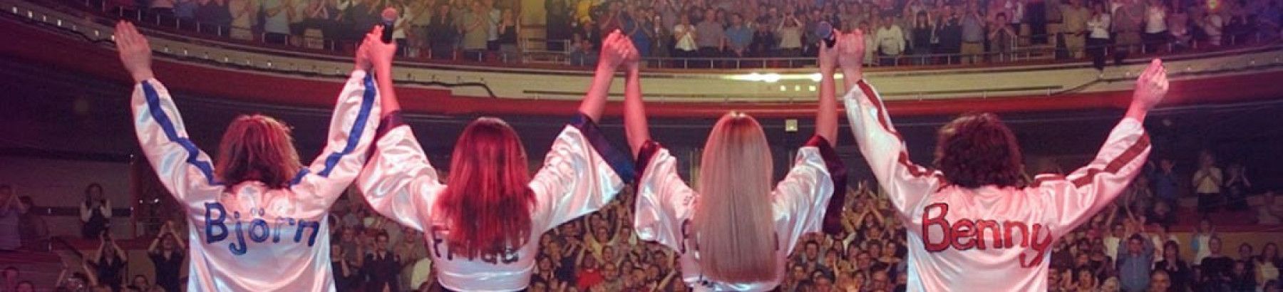 Four people standing on stage with an audience