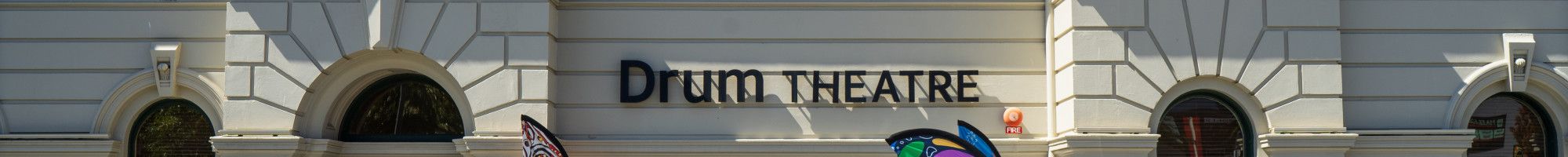 View of the facade of The Drum theatre with plants and flags.